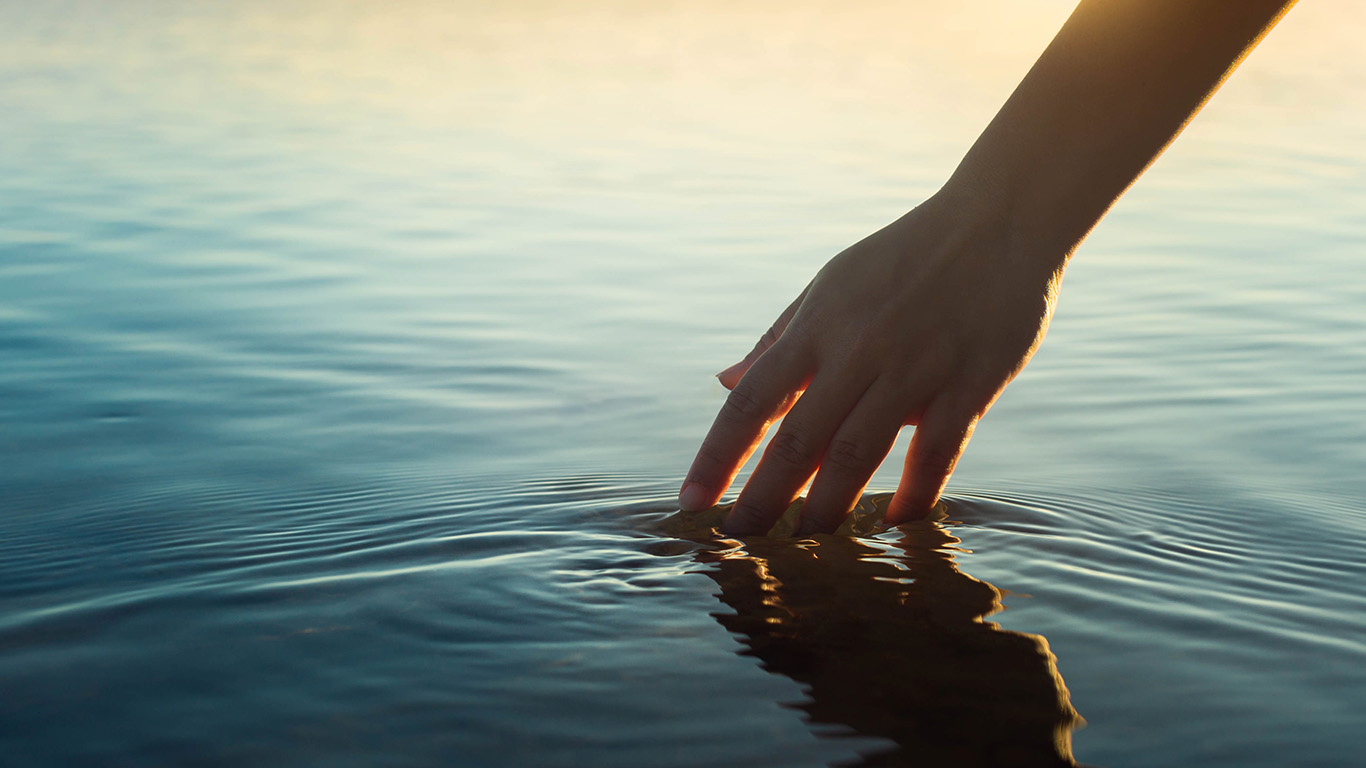 A woman gently touching water in reflection